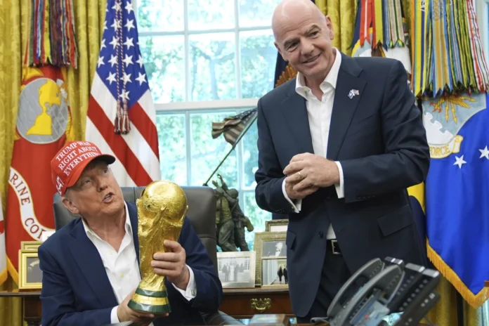 President Donald Trump holds the FIFA World Cup Winners Trophy as FIFA President Gianni Infantino looks on during an announcement in the Oval Office of the White House
